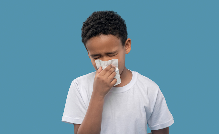 Boy sneezing into tissue - toolkit for preventing respiratory illness